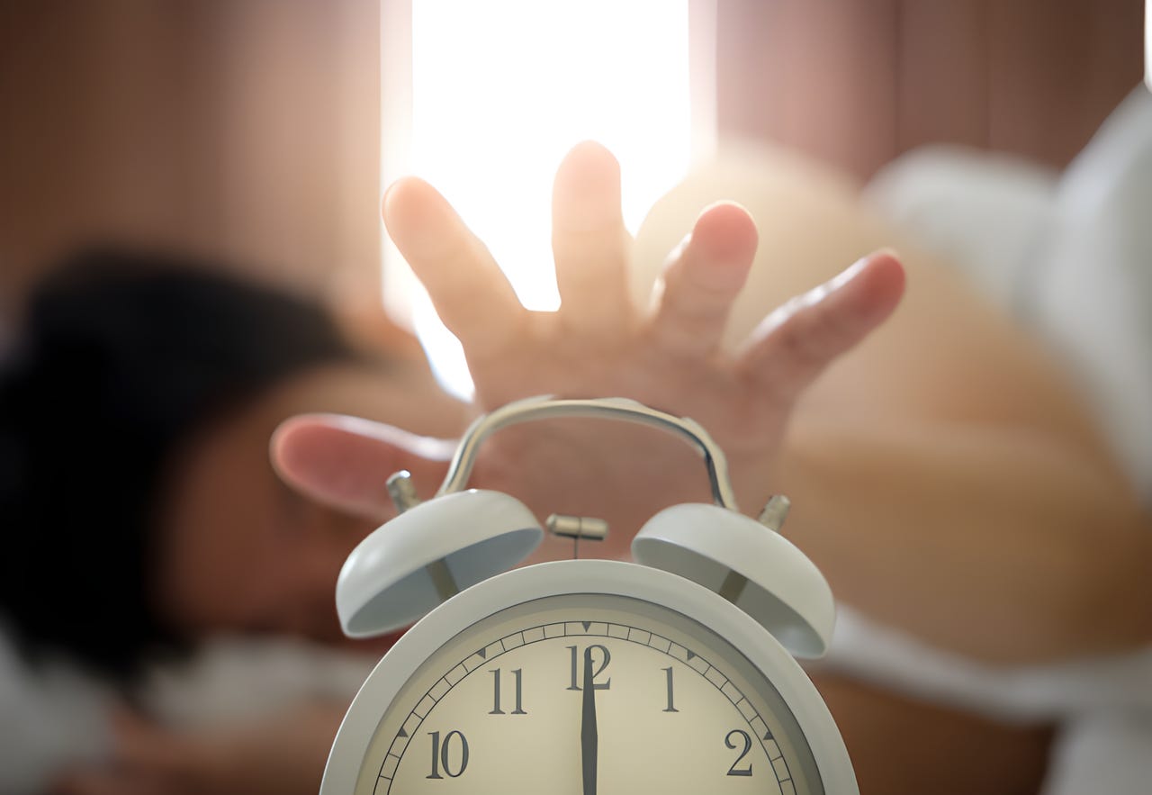 Hand reaching for an alarm clock. Hand reaching for an alarm clock.