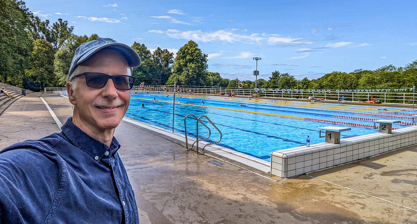 Michael standing in front of an outdoor swimming pool on a sunny Sunday. 