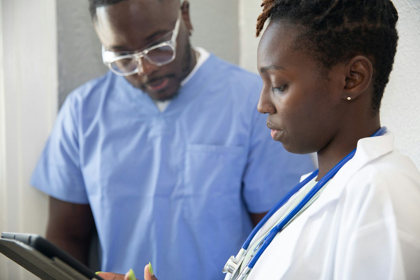 A man and woman in hospital garb look at a tablet. Photo by Nappy on Unsplash