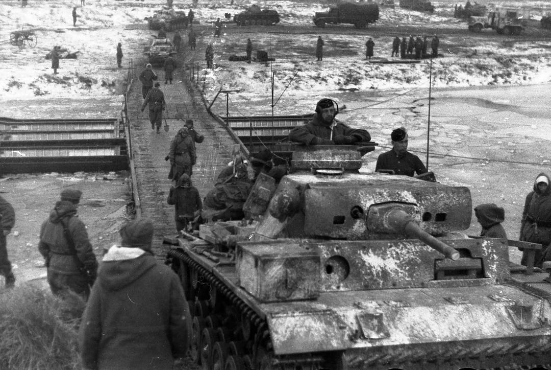 Heer soldiers and a Panzer III tank meticulously cross a makeshift bridge over a frozen river during the brutal Operation Winter Storm, southwest of Stalingrad, December 1942.