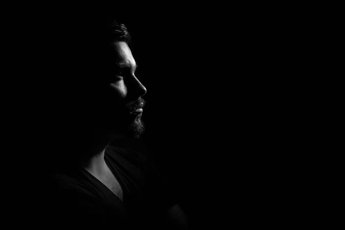 grayscale photo of man in black v neck shirt with black background