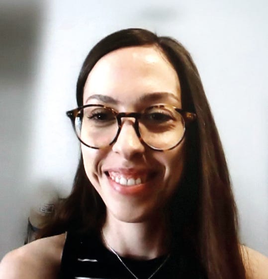 O Gemini disseUma mulher de cabelos longos e castanhos sorri para a câmera. Ela usa óculos de armação redonda com estampa de casco de tartaruga e uma blusa preta. O fundo é uma parede clara e lisa. O Gemini disseUma mulher de cabelos longos e castanhos sorri para a câmera. Ela usa óculos de armação redonda com estampa de casco de tartaruga e uma blusa preta. O fundo é uma parede clara e lisa.