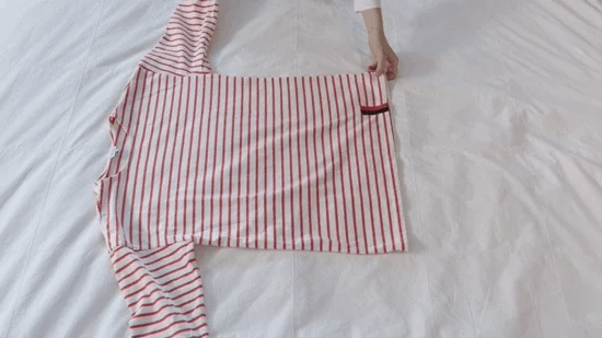 A woman folds a shirt neatly. A woman folds a shirt neatly.