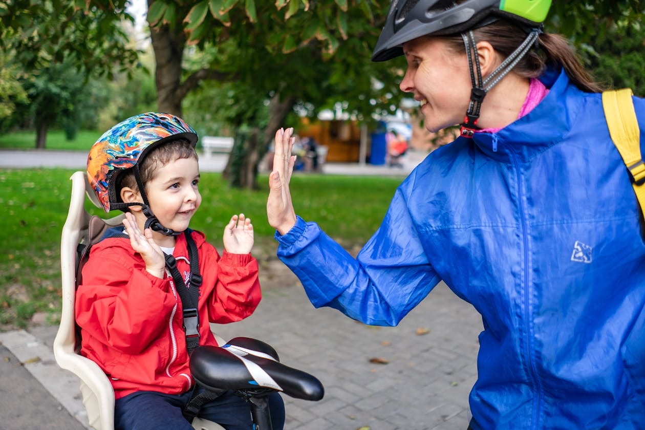 Madre e hijo dando choca los cinco en bicicleta Madre e hijo dando choca los cinco en bicicleta