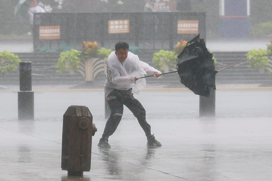 A man holds tightly onto an umbrella that is blown open by the wind during Typhoon Dolphin in Shanghai, on 9 August.