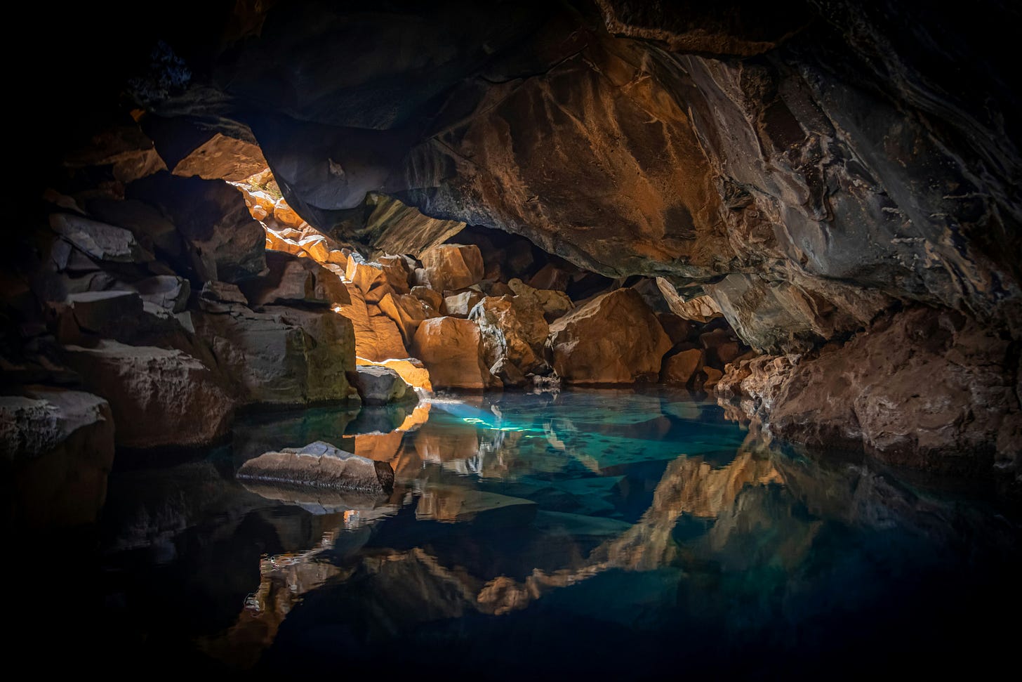 Beautiful photo of a rocky cave with a crystal blue pool of water and a bright sliver of sunlight Beautiful photo of a rocky cave with a crystal blue pool of water and a bright sliver of sunlight
