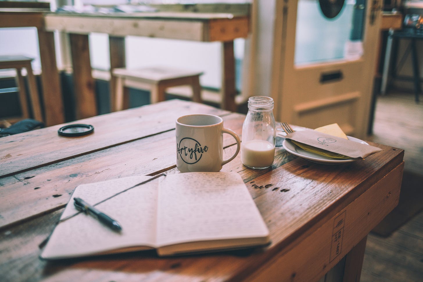 Image of a coffee mug and a notebook on a table.