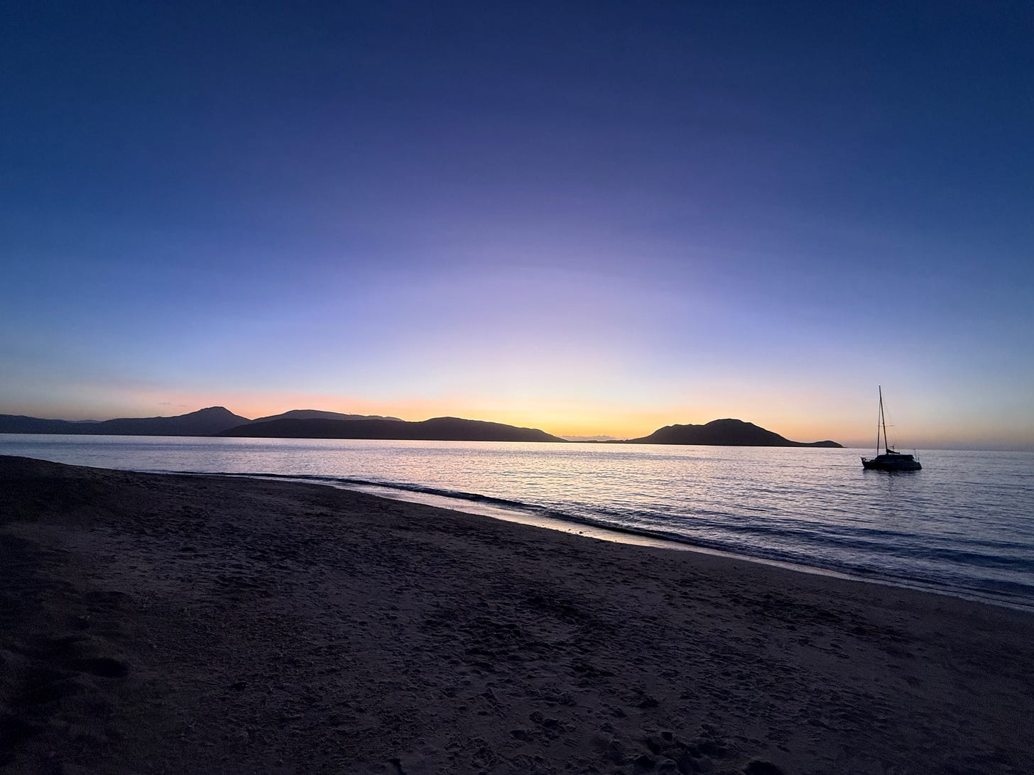 beach in Australia at dusk. calm water reflecting sunset with a small boat beach in Australia at dusk. calm water reflecting sunset with a small boat