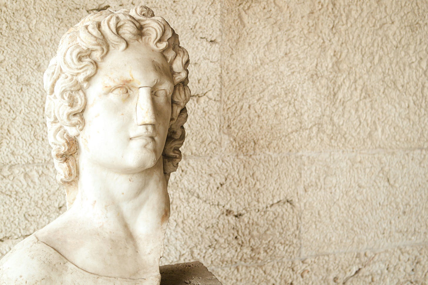 Marble bust of a young male figure in classical style, often associated with Alexander the Great, with wavy hair and an upward gaze. Marble bust of a young male figure in classical style, often associated with Alexander the Great, with wavy hair and an upward gaze.
