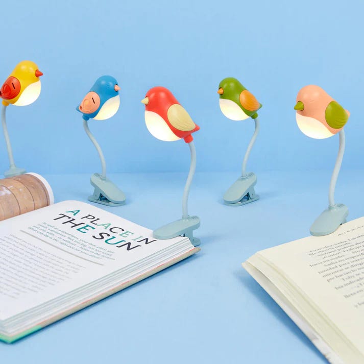 lámparas para lectura con forma de tulipán y pájaros de colores sujetas en libros
