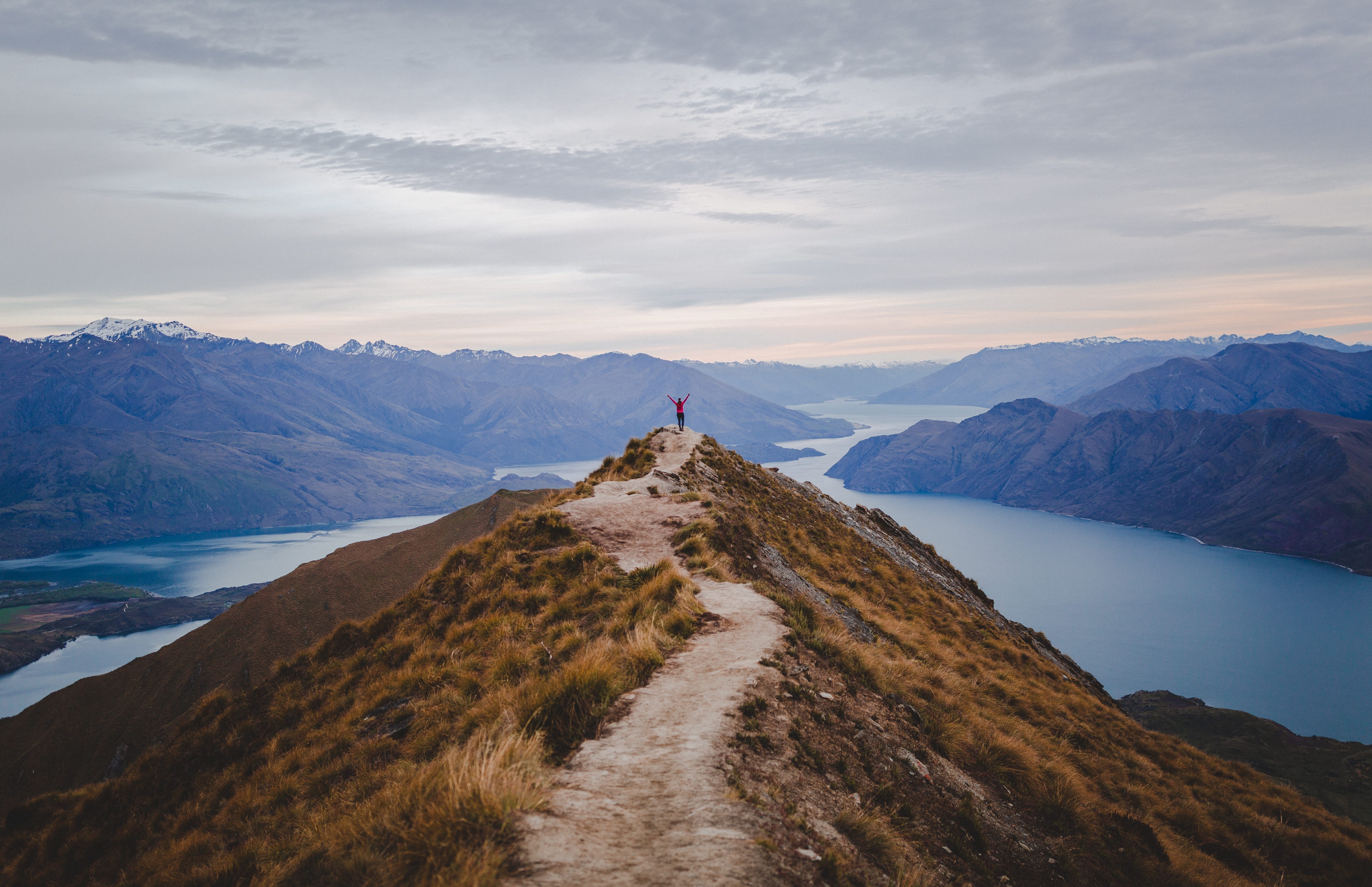 Woman with raised arms on top of a mountain peak.