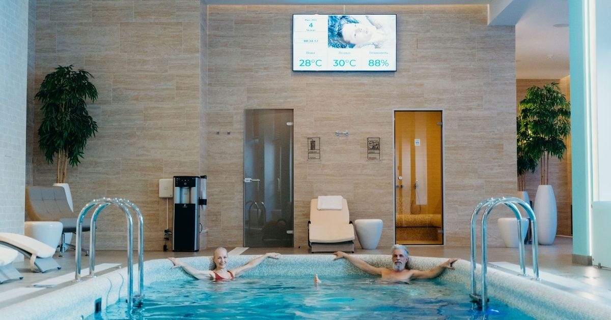 Two adults enjoying leisure time at an indoor swimming pool with spa-like ambiance