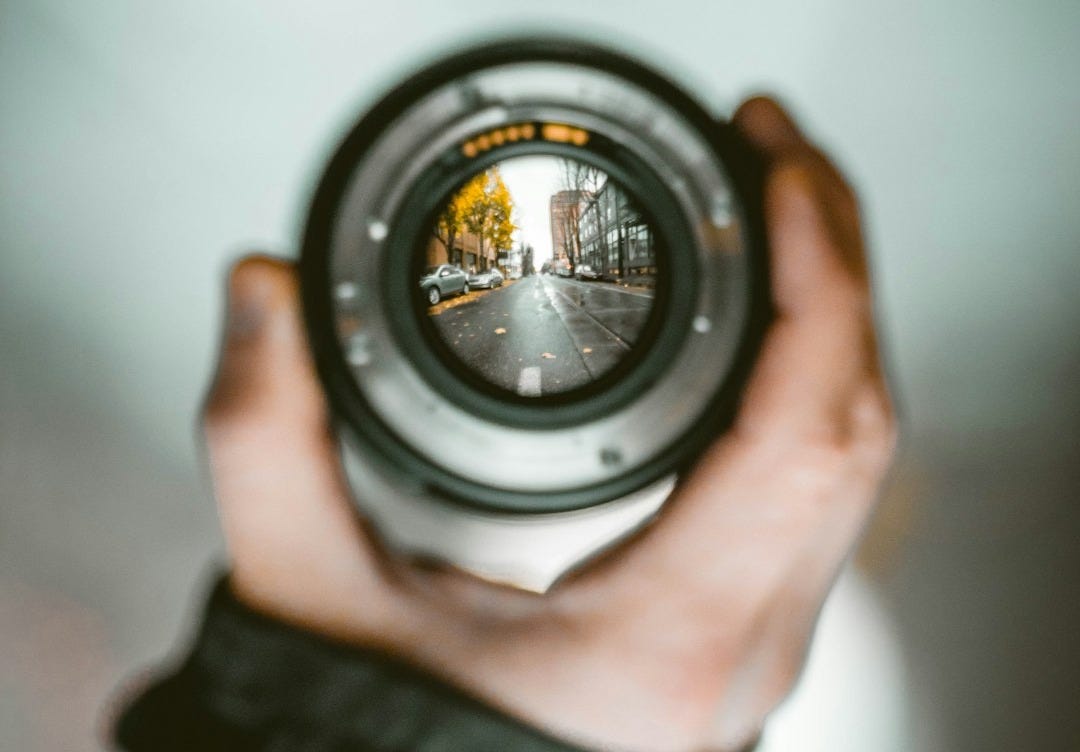 person holding camera lens person holding camera lens