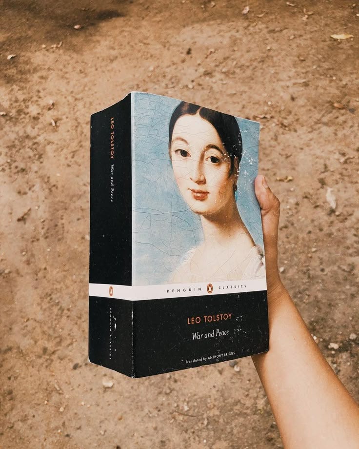 This may contain: a person holding up a book with an image of a woman's face on it