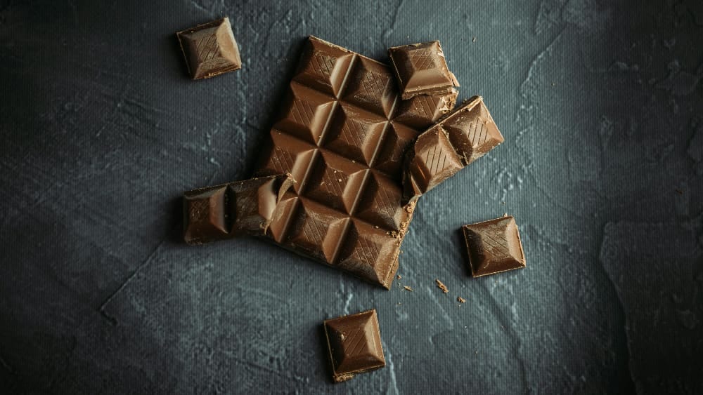 Squares of chocolate on a dark gray background Squares of chocolate on a dark gray background