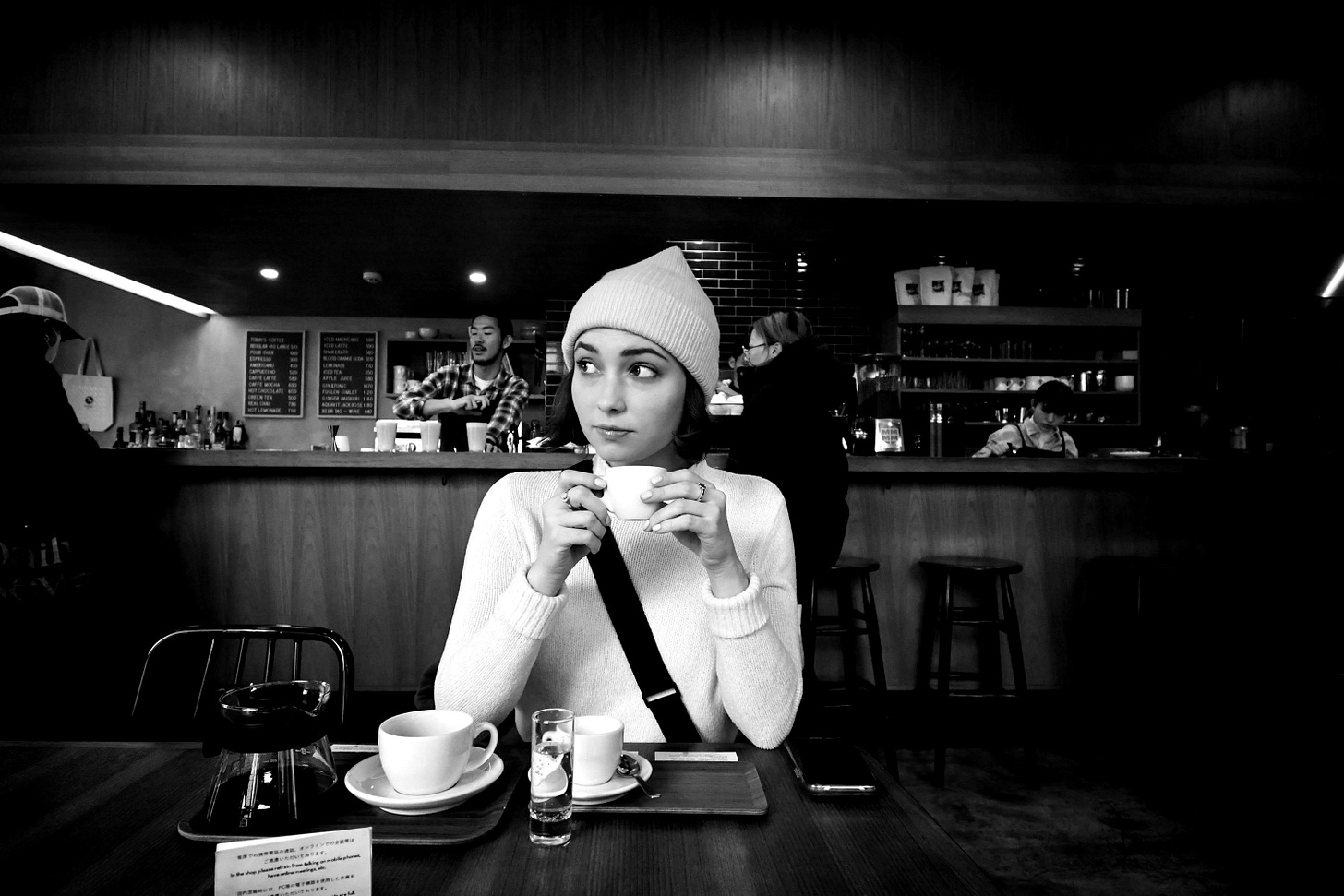 a woman sitting at a table with a cup of coffee a woman sitting at a table with a cup of coffee