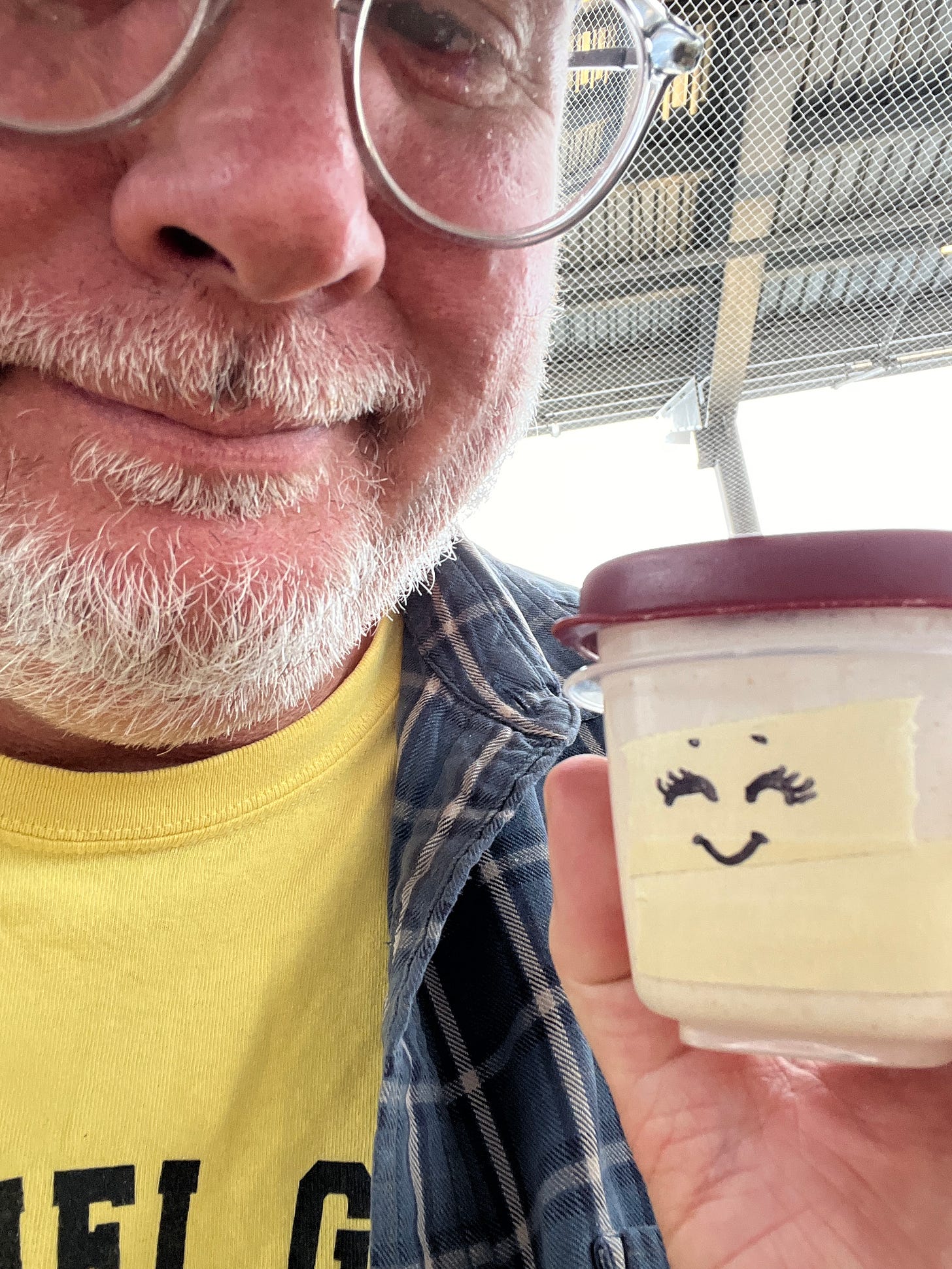 me holding a tiny tupperware container with a little cartoon face drawn on the side