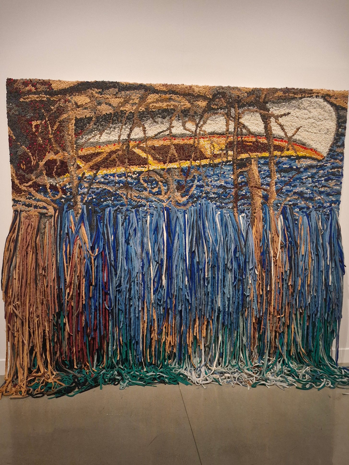 an artwork made of strips of material. the top part is an image of an uspide down canoe, and then the material strips fall down like a waterfall to the floor an artwork made of strips of material. the top part is an image of an uspide down canoe, and then the material strips fall down like a waterfall to the floor