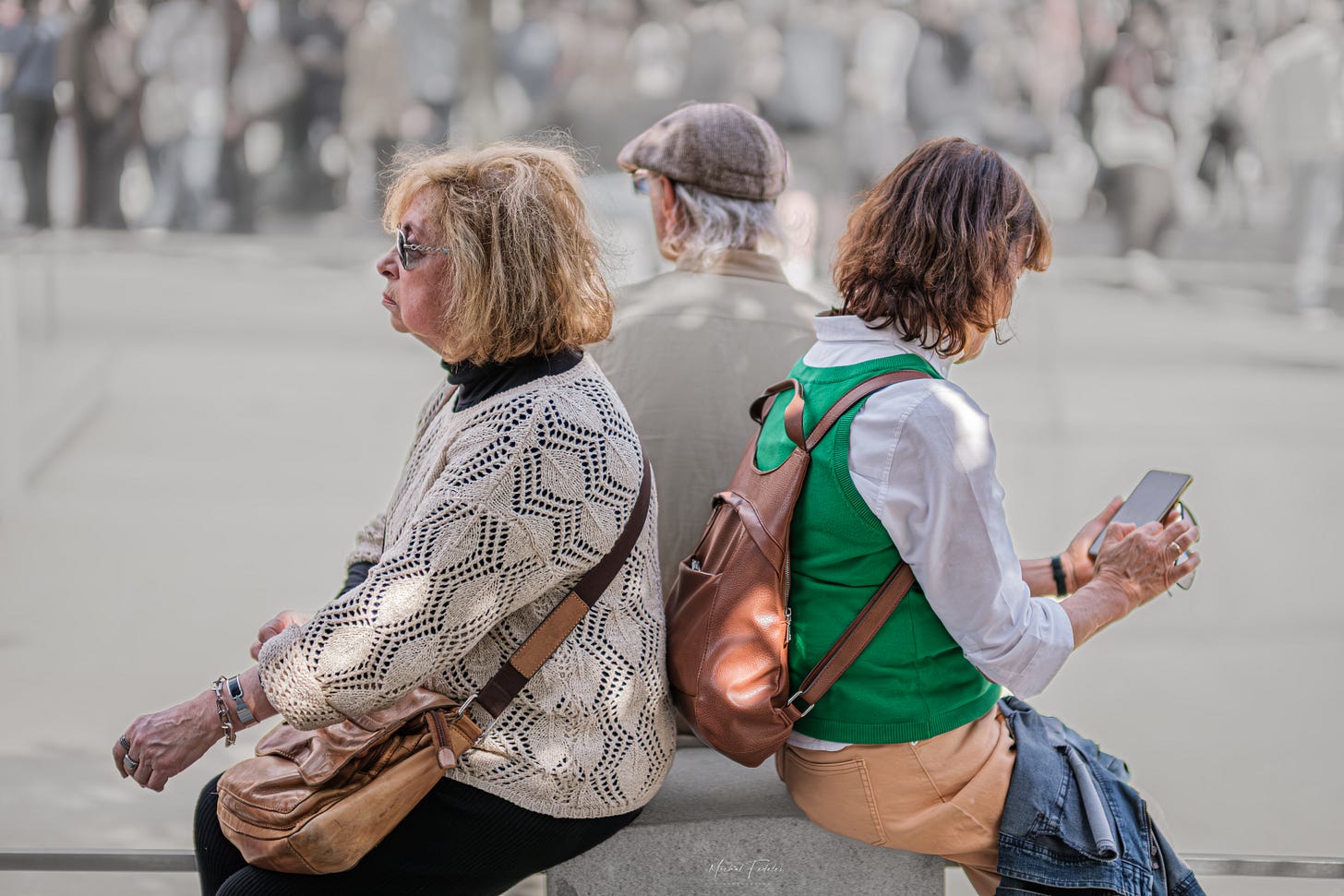 Two older adults and a younger woman sitting with their backs to one another Two older adults and a younger woman sitting with their backs to one another