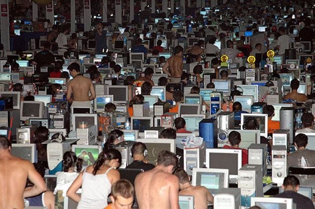 This may contain: a large group of people standing in front of rows of computer monitors and laptops
