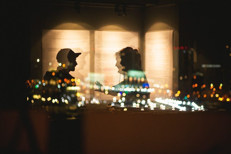a blurred couple in front of a window, overlooking city lights. indicative of the action-reaction-retraction cycle. a blurred couple in front of a window, overlooking city lights. indicative of the action-reaction-retraction cycle.
