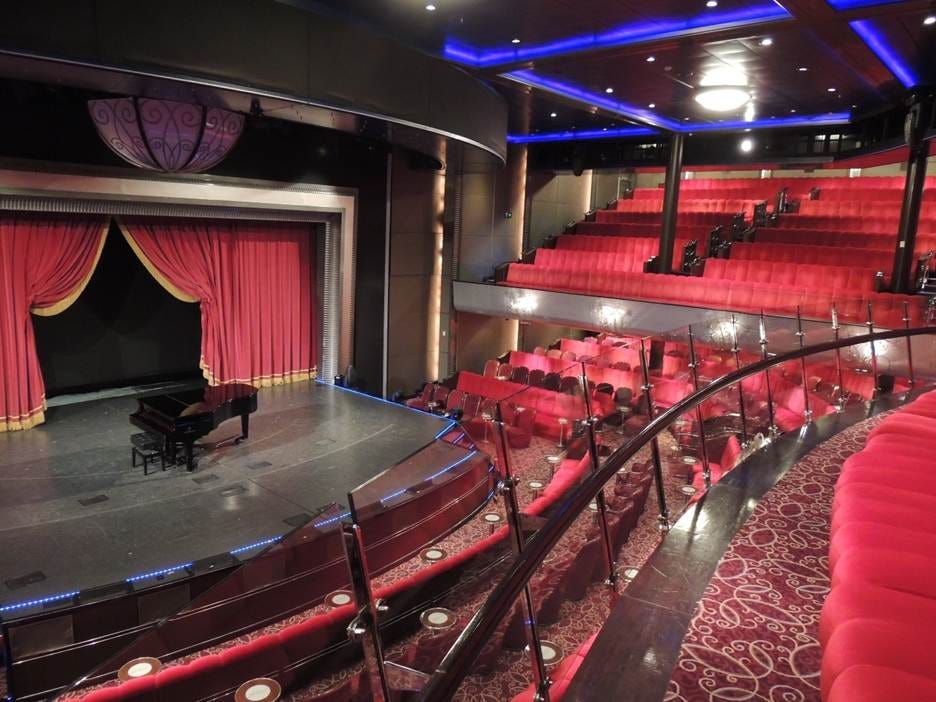 A stage with red seats and a piano

AI-generated content may be incorrect.