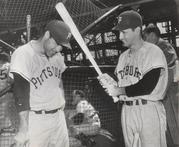 Tommy O'Brien pretends to bounce a bat off Joe Garagiola's helmeted head.