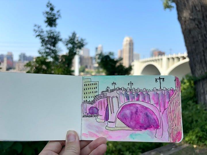 Hand holding up drawing of bridge in downtown Minneapolis
