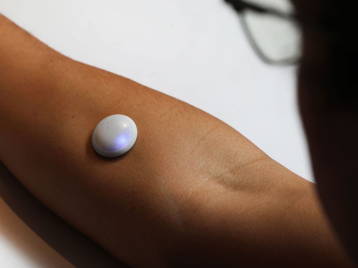 a white dot with a glowing blue light on top of a person's forearm a white dot with a glowing blue light on top of a person's forearm