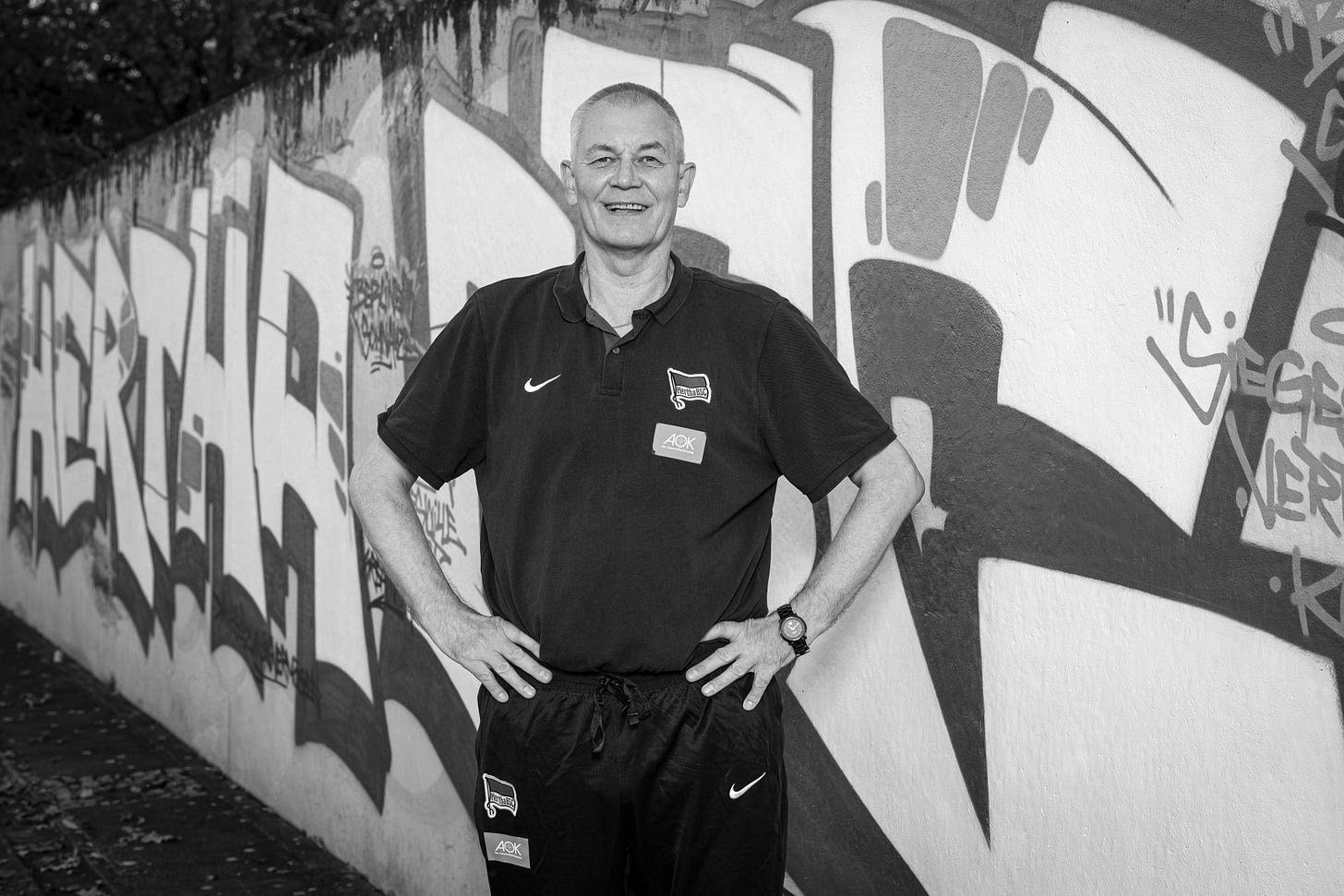 Michael Schröder steht vor einer Mauer auf dem Olympiagelände.