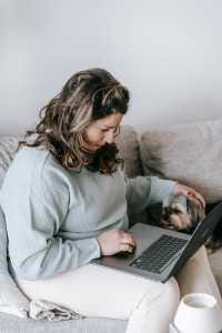 woman sitting on sofa while using a laptop