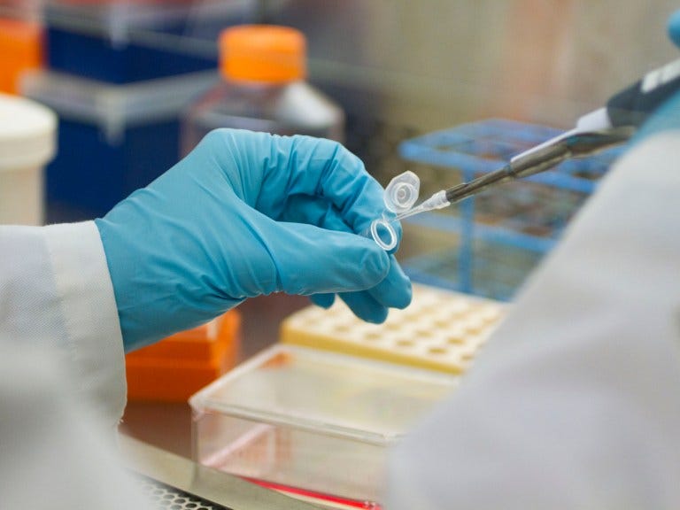 A gloved hand using lab equipment