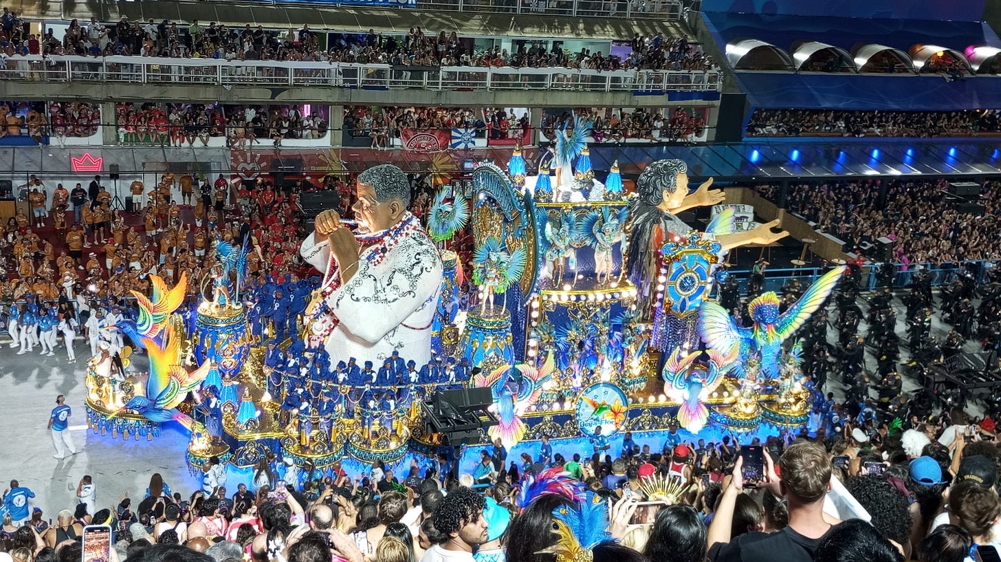 Imagem de carro alegórico da BeijaFlor em 2025 que mostra Laíla e Joãosinho Trinta. Visão lateral, das arquibancadas. Imagem de carro alegórico da BeijaFlor em 2025 que mostra Laíla e Joãosinho Trinta. Visão lateral, das arquibancadas.