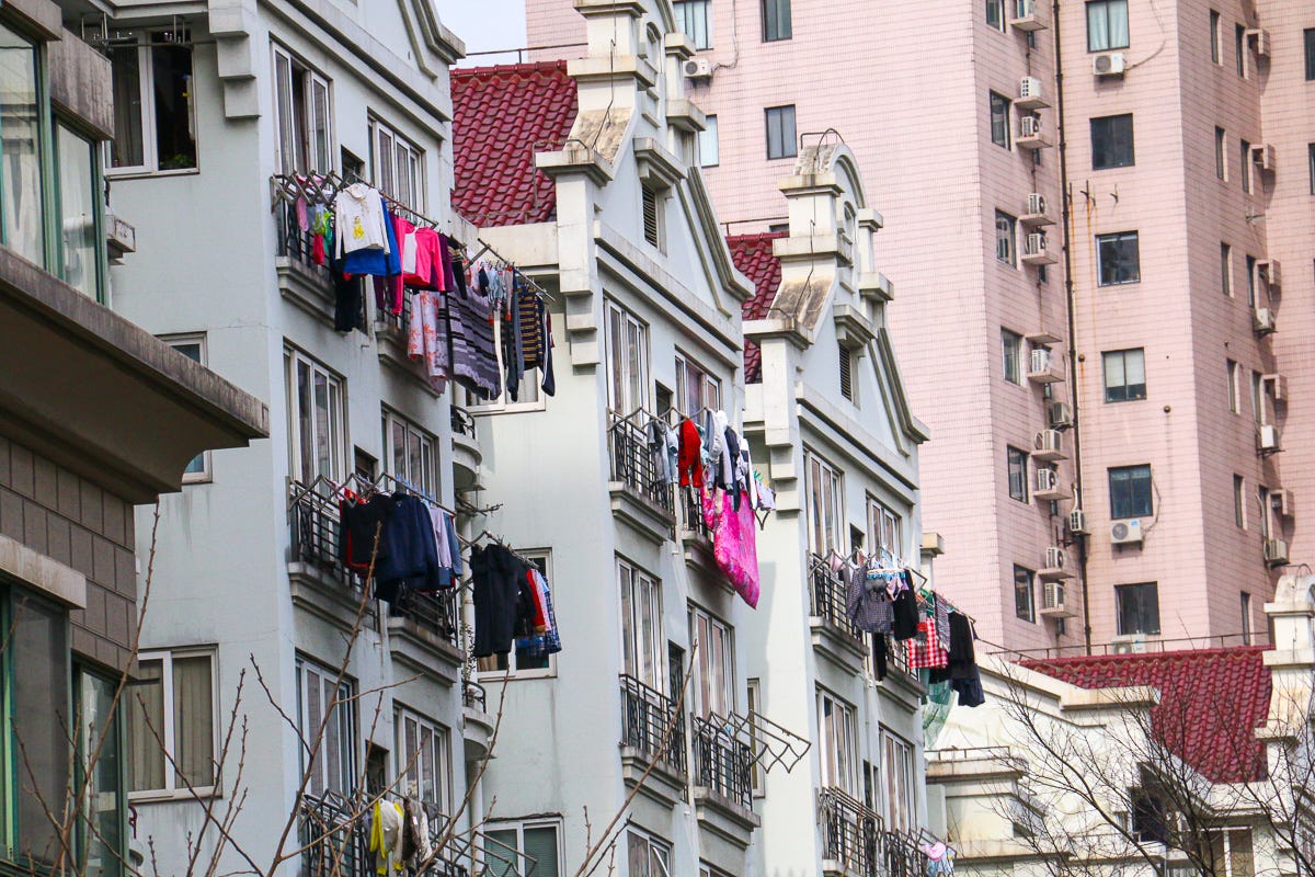 Dozens of balconies on neighboring apartment buildings covered in colorful hanging clothes. A visual rhythm of daily life in vertical density.