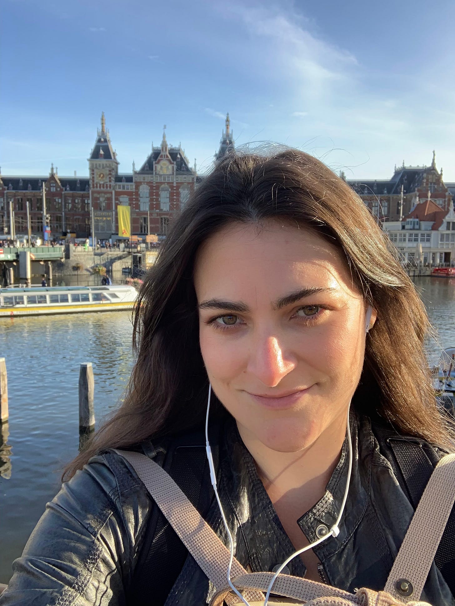 A dark haired woman smiles into the camera in Amsterdam.
