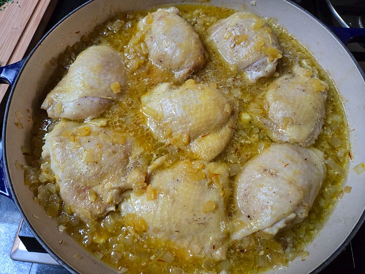 Left: braiser with eight chicken thighs in a saffron-colored oniony liquid. Right: Chopped parsley, halved olives, and whole preserved lemons, quartered, on a cutting board.