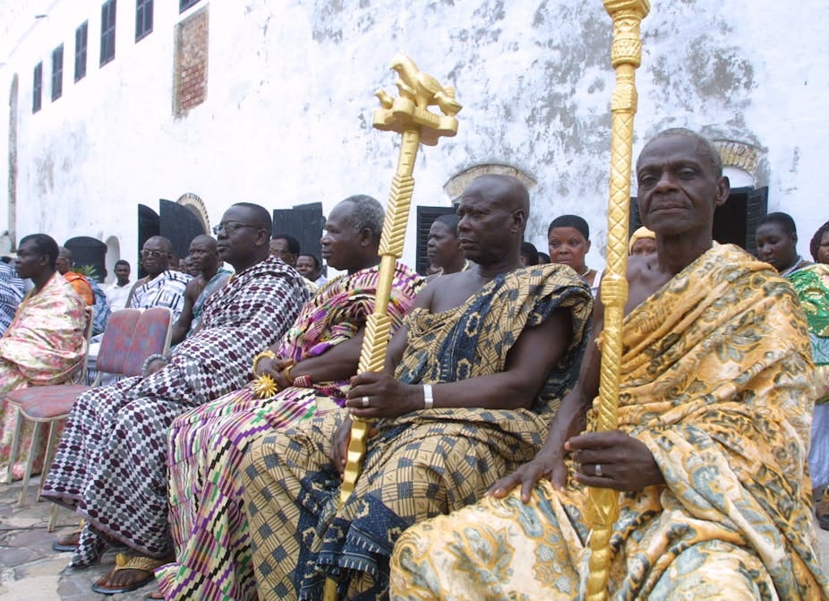 Men seated in a group holding staffs Men seated in a group holding staffs