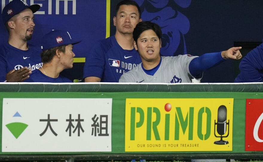 Los Angeles Dodgers' Yoshinobu Yamamoto, left, and Shohei Ohtani, right, talk as they sit in the dugout in the ninth inning of an MLB Japan Series baseball game against the Los Angeles Dodgers in Tokyo, Japan, Tuesday, March 18, 2025. (AP Photo/Hiro Komae)