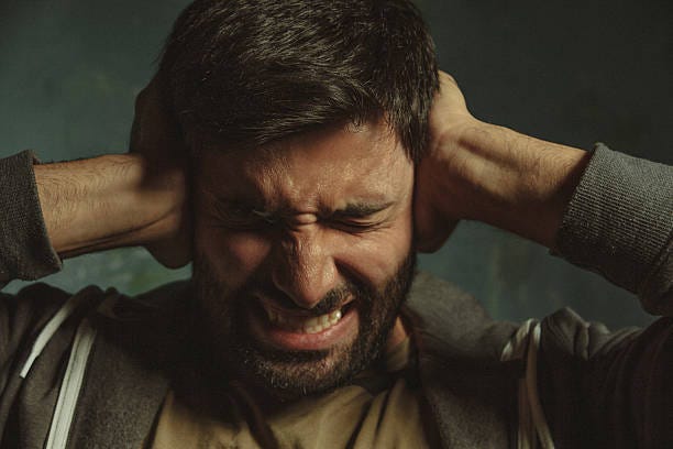 Annoyed young man closing ear with hand Close up portrait of young man in pain closing eyes and plugging ears with his hands protecting from loud noise cover ears stock pictures, royalty-free photos & images