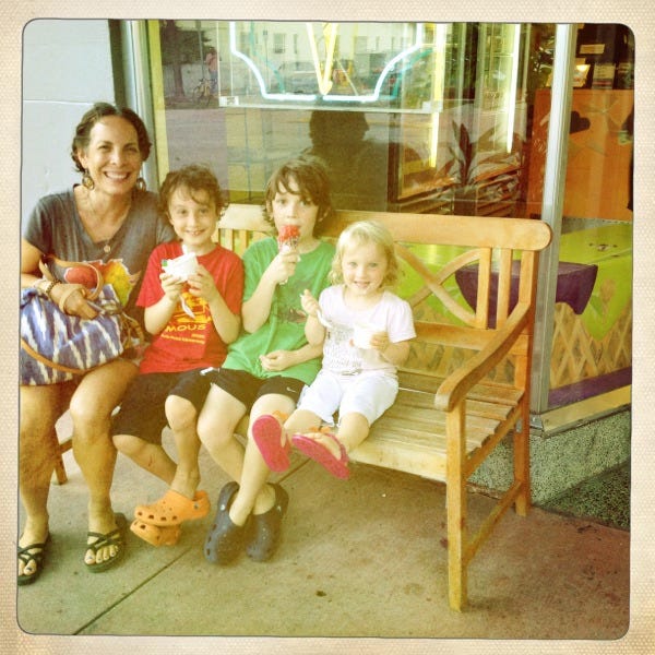 Prescott and her three kids, sitting on a bench outside and eating popsicles Prescott and her three kids, sitting on a bench outside and eating popsicles