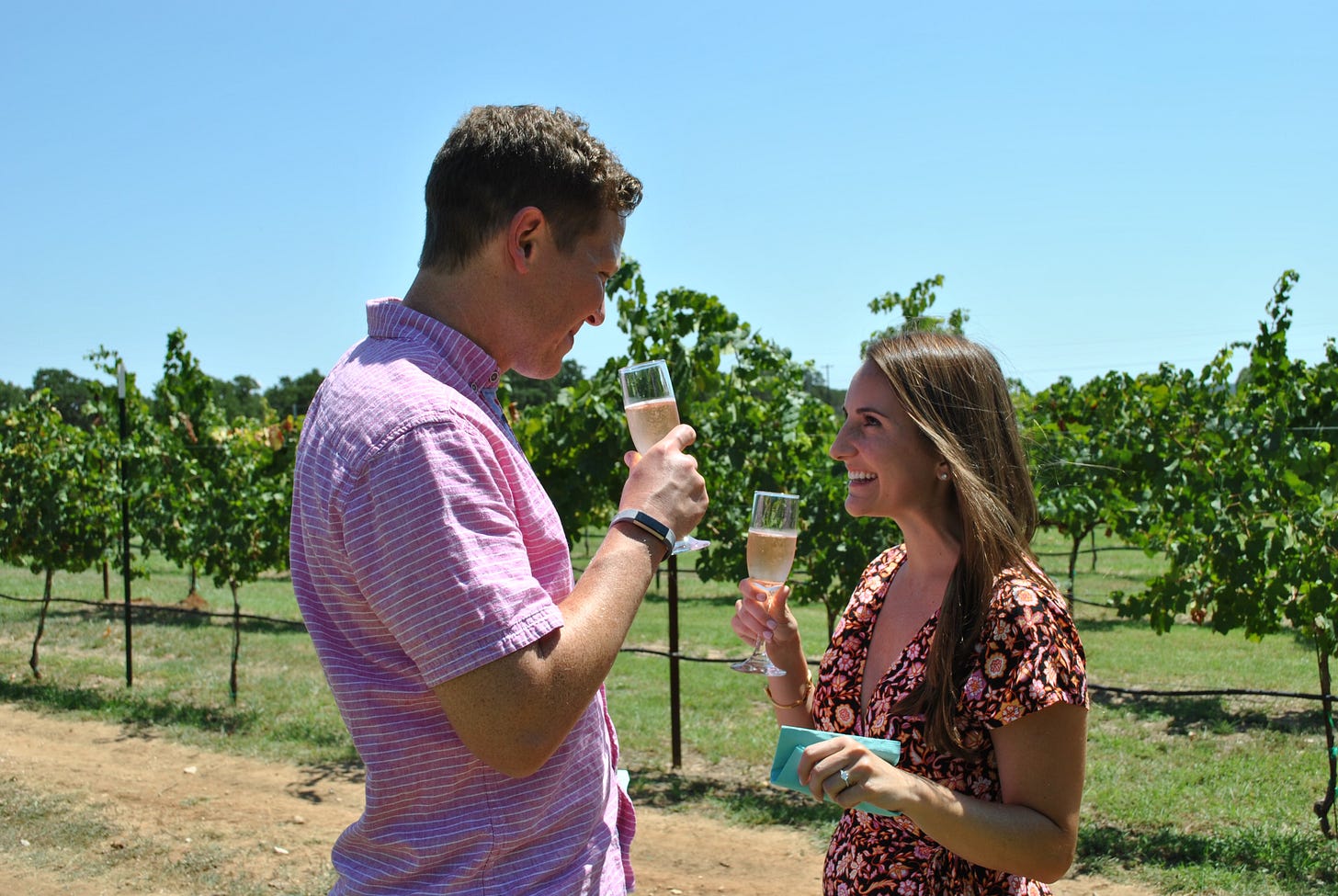 A man and a woman looking at each other and smiling standing in a vineyard A man and a woman looking at each other and smiling standing in a vineyard