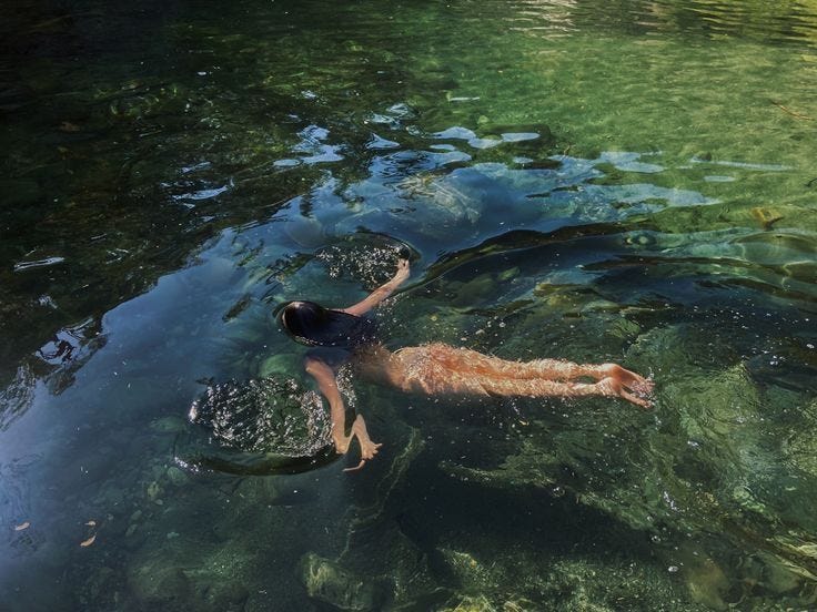 This may contain: a person swimming in the water with their arms up This may contain: a person swimming in the water with their arms up