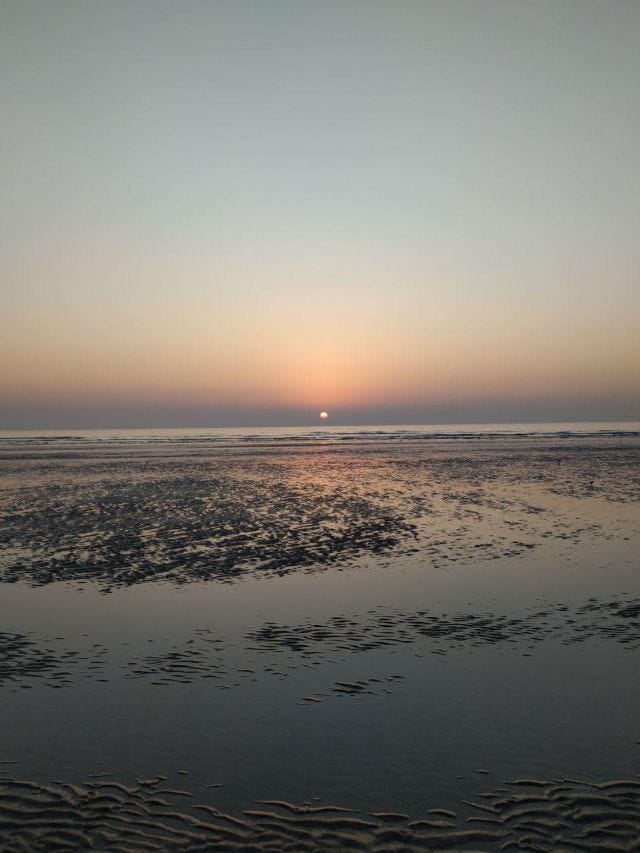 A sunset at a beach with waves behind A sunset at a beach with waves behind