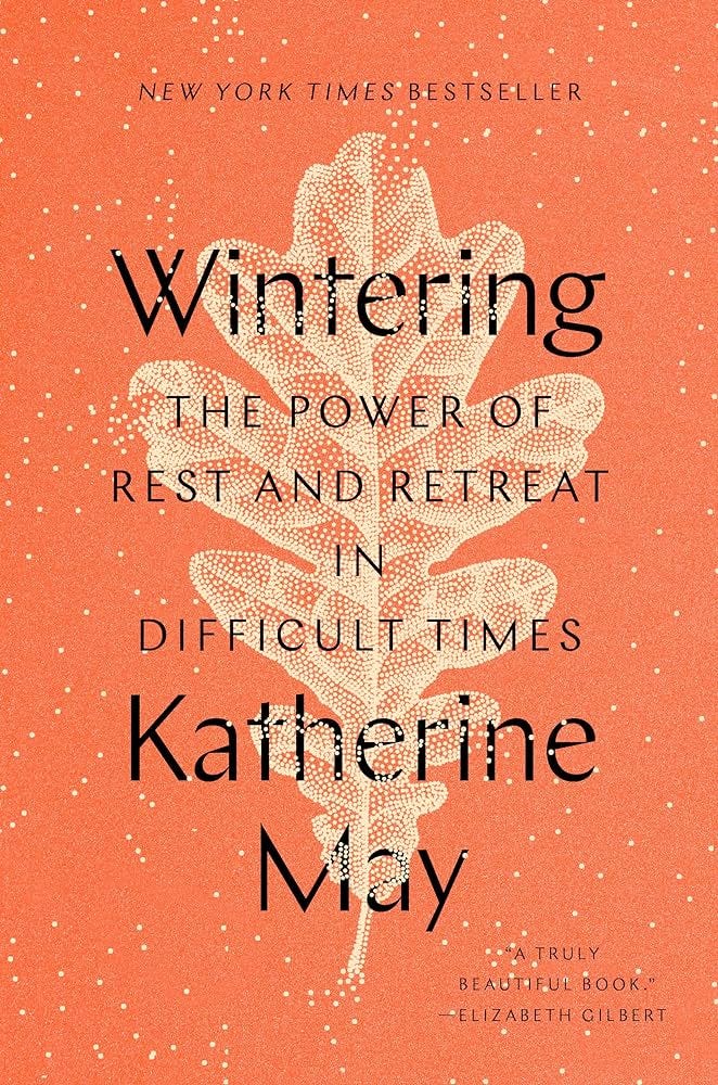 An orange book cover with a white leaf and the title "Wintering: The Power of Rest and Retreat in Difficult Times by Katherine May" in the center