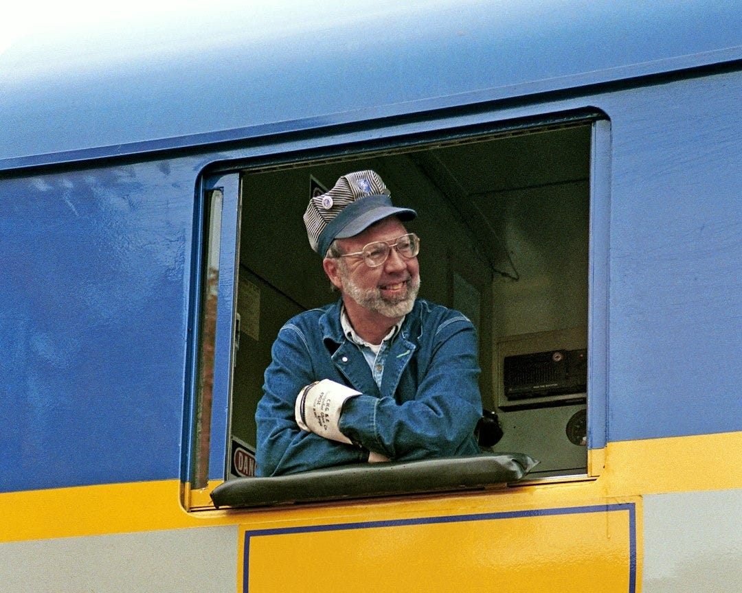 A train driver smiles from the train's window.