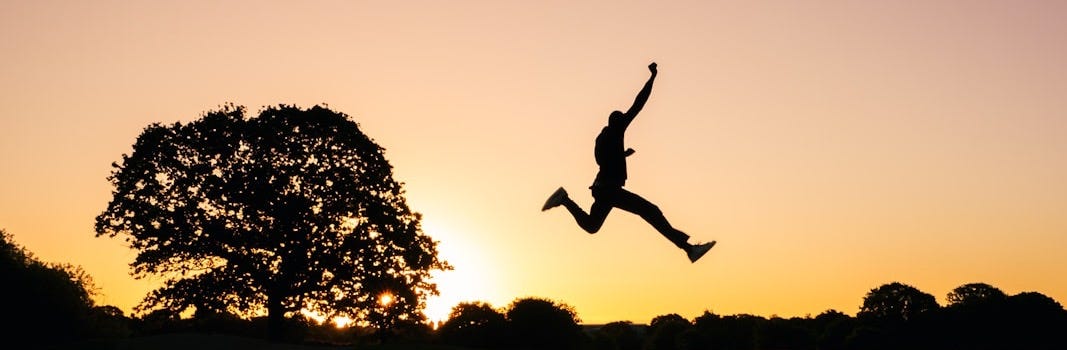 silhouette photo of man jumping on body of water during golden hour