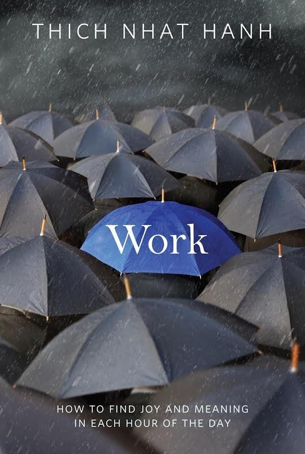 Pictured are a crowd of dark blue umbrellas in the rain with one light blue umbrella in the center of the cover with the tile “Work” on top of the light blue umbrella.