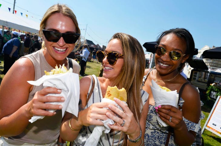 Three women holding street food dishes and smiling in the sun Three women holding street food dishes and smiling in the sun