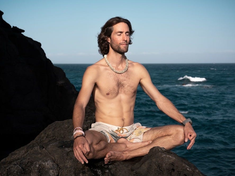 topless man in brown shorts sitting on rock near sea during daytime topless man in brown shorts sitting on rock near sea during daytime