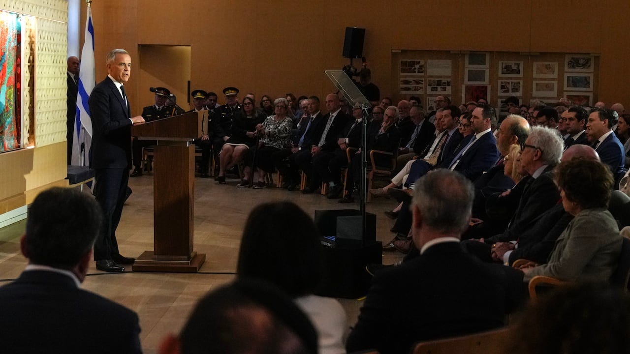 A man speaks at a podium with an Israeli flag nearby A man speaks at a podium with an Israeli flag nearby